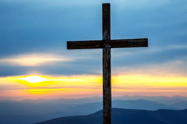 wooden cross on a background of sunrise in the mountains