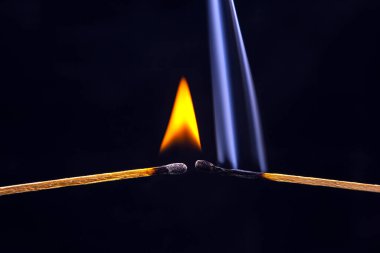 Ateş ve duman. Siyah arka planda yanan ve tüten kibrit. Sıcaklık ve alevlerin ışığı