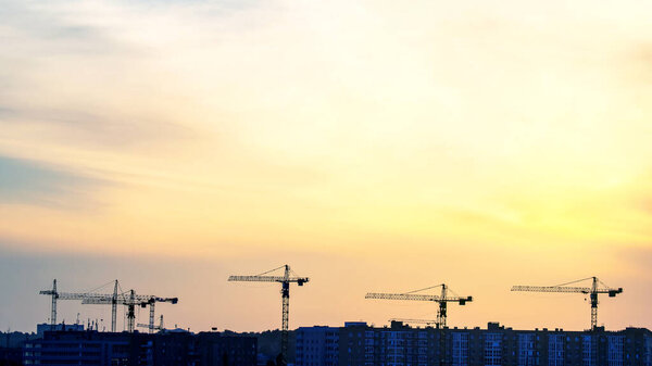 Silhouettes of building cranes in the evening sky against the backdrop of sunset. urban building industry