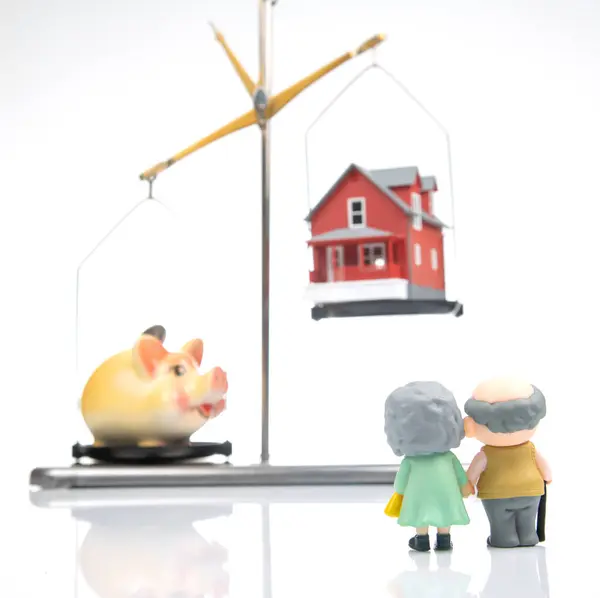 stock image Pensioners stand near a piggy bank with a house on the scales. The concept of accumulating finances to buy a house for living. home real estate financial investment