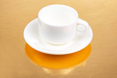 Altın zemin üzerinde fincan tabağı olan beyaz kahve fincanı