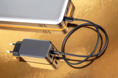 Güç bankası ve altın arka planda şarj prizi. Cihazları şarj etmek için elektronik aygıtlar