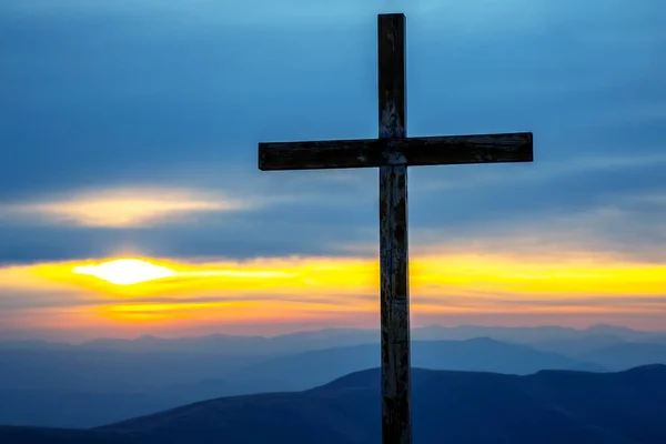 wooden cross on a background of sunrise in the mountains