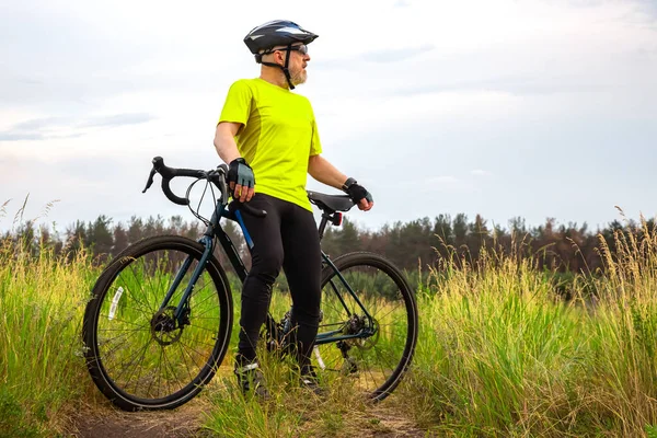 身穿黄色衣服的满脸胡须的骑自行车的人正在大自然的路上骑自行车休息 业余爱好和娱乐促进健康 免版税图库照片