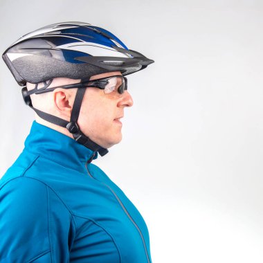 Bisiklet kasklı ve arka planda şeffaf gözlüklü bir erkek bisikletçi.
