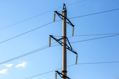 Mavi gökyüzünün arka planında voltaj iletim kabloları olan elektrik kulesi. Yüksek voltaj kulesi. Elektrik iletimi için kablolarla elektrik hattı desteği. Enerji endüstrisi.