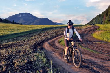Bisikletçi adam güzel bir doğada yol boyunca bisiklet sürüyor. Spor ve hobiler