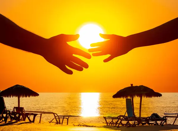silhouette of male and female hands on the background of a sea sunset. concept of communication and striving for closeness in society and family