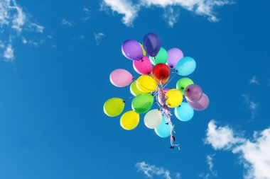 Mavi gökyüzünde uçan bir sürü renkli balon. Tatil aksesuarları ve dekorasyonları