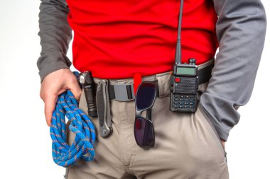 Kalem, bıçak ve el feneri. Pantolonun kemerinde klipsleri var. EDC ögeleri