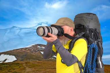 Sırt çantalı bir turist fotoğrafçısı dağlardaki doğanın güzelliğini fotoğraflıyor.