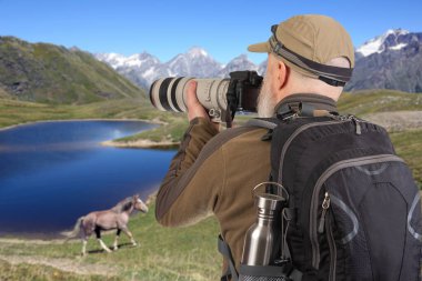 Sırt çantalı bir turist fotoğrafçısı dağlardaki doğanın güzelliğini fotoğraflıyor. Dağlarda doğa yürüyüşleri