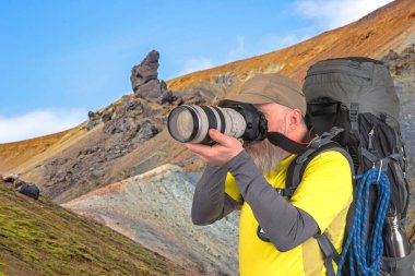 Sırt çantalı bir turist fotoğrafçısı dağlardaki doğanın güzelliğini fotoğraflıyor.