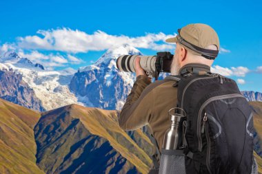 Sırt çantalı bir turist fotoğrafçısı dağlardaki doğanın güzelliğini fotoğraflıyor. Dağlarda doğa yürüyüşleri