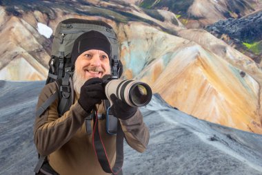 Sırt çantalı sakallı turist fotoğrafçı dağlardaki doğanın güzelliğini fotoğraflıyor. Dağlarda doğa yürüyüşleri