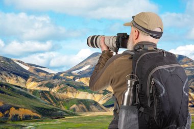 Sırt çantalı bir turist fotoğrafçısı dağlardaki doğanın güzelliğini fotoğraflıyor. Dağlarda doğa yürüyüşleri