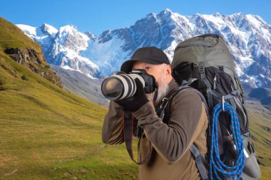 Sırt çantalı sakallı turist fotoğrafçı dağlardaki doğanın güzelliğini fotoğraflıyor. Dağlarda doğa yürüyüşleri