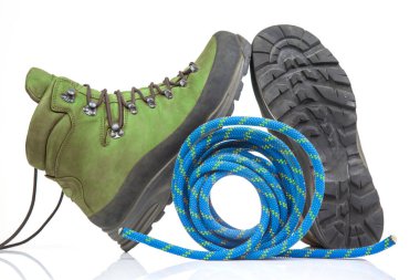 Beyaz arka planda tırmanma ipinin yanında yürüyüş botları. Seyahat ve Yürüyüş Ekipmanı