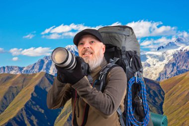 Sırt çantalı sakallı turist fotoğrafçı dağlardaki doğanın güzelliğini fotoğraflıyor. Dağlarda doğa yürüyüşleri