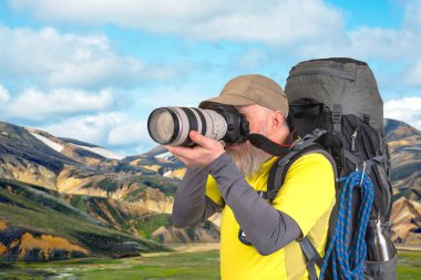 Sırt çantalı bir turist fotoğrafçısı dağlardaki doğanın güzelliğini fotoğraflıyor.