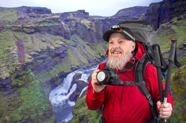 Sırt çantalı sakallı turist fotoğrafçı dağlardaki doğanın güzelliğini fotoğraflıyor. Dağlarda doğa yürüyüşleri