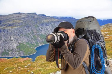 Sırt çantalı sakallı turist fotoğrafçı dağlardaki doğanın güzelliğini fotoğraflıyor. Dağlarda doğa yürüyüşleri