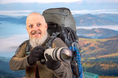Sırt çantalı sakallı turist fotoğrafçı dağlardaki doğanın güzelliğini fotoğraflıyor. Dağlarda doğa yürüyüşleri