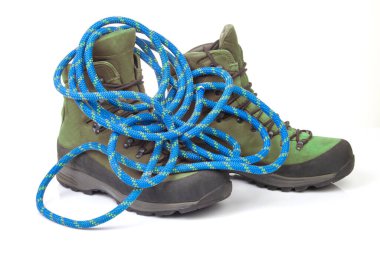 Beyaz arka planda tırmanma ipinin yanında yürüyüş botları. Seyahat ve Yürüyüş Ekipmanı