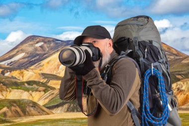 Sırt çantalı sakallı turist fotoğrafçı dağlardaki doğanın güzelliğini fotoğraflıyor. Dağlarda doğa yürüyüşleri