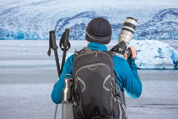 Sırt çantalı erkek turist fotoğrafçı dağlardaki doğanın güzelliğine bakıyor. Dağlarda doğa yürüyüşleri