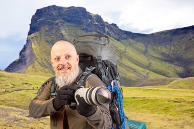 Sırt çantalı sakallı turist fotoğrafçı dağlardaki doğanın güzelliğini fotoğraflıyor. Dağlarda doğa yürüyüşleri