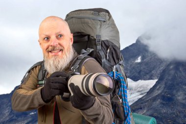 Sırt çantalı sakallı turist fotoğrafçı dağlardaki doğanın güzelliğini fotoğraflıyor. Dağlarda doğa yürüyüşleri