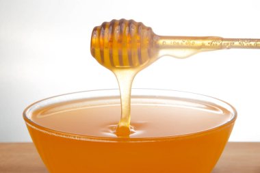 Beyaz arka planda şeffaf bir plakaya damlayan taze bal. organik vitamin sağlıklı gıdalar