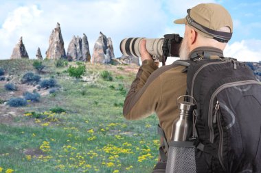 Sırt çantalı bir turist fotoğrafçısı dağlardaki doğanın güzelliğini fotoğraflıyor. Dağlarda doğa yürüyüşleri