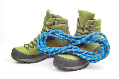 Beyaz arka planda tırmanma ipinin yanında yürüyüş botları. Seyahat ve Yürüyüş Ekipmanı