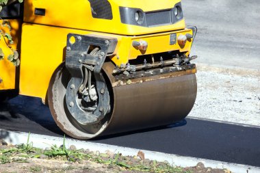 Asfalt silindiri yayalar için bir yol onarıyor