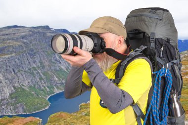 Sırt çantalı bir turist fotoğrafçısı dağlardaki doğanın güzelliğini fotoğraflıyor. Dağlarda doğa yürüyüşleri