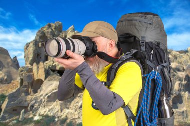 Sırt çantalı bir turist fotoğrafçısı dağlardaki doğanın güzelliğini fotoğraflıyor. Dağlarda doğa yürüyüşleri