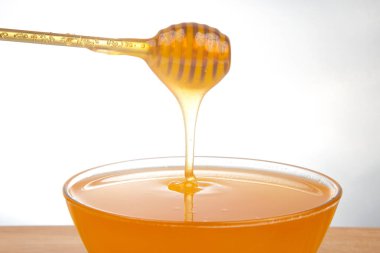 Beyaz arka planda şeffaf bir plakaya damlayan taze bal. organik vitamin sağlıklı gıdalar