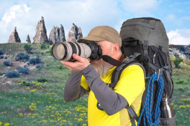 Sırt çantalı bir turist fotoğrafçısı dağlardaki doğanın güzelliğini fotoğraflıyor. Dağlarda doğa yürüyüşleri