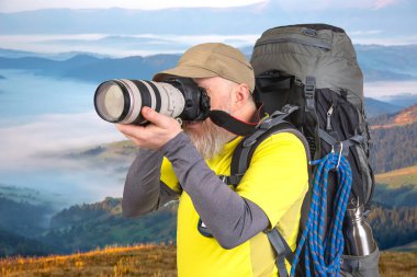 Sırt çantalı bir turist fotoğrafçısı dağlardaki doğanın güzelliğini fotoğraflıyor.
