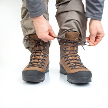 Beyaz arka planda bir turistin bacaklarında yürüyüş yaptığın için çizme giyiyorsun. Seyahat ve yürüyüş ekipmanları