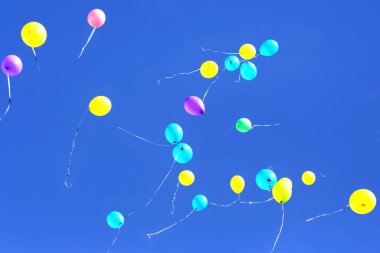 Mavi gökyüzünde uçan bir sürü renkli balon. Tatil aksesuarları ve dekorasyonları