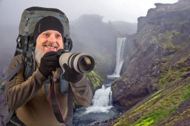 Sırt çantalı sakallı turist fotoğrafçı dağlardaki doğanın güzelliğini fotoğraflıyor. Dağlarda doğa yürüyüşleri