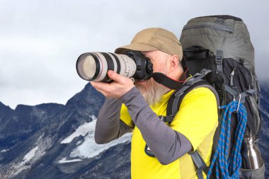 Sırt çantalı bir turist fotoğrafçısı dağlardaki doğanın güzelliğini fotoğraflıyor. Dağlarda doğa yürüyüşleri