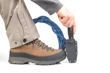 Tırmanma ipinin yanında yürüyüş botları ve beyaz arka planda bir bıçak. Seyahat ve Yürüyüş Ekipmanı