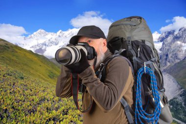 Sırt çantalı sakallı turist fotoğrafçı dağlardaki doğanın güzelliğini fotoğraflıyor. Dağlarda doğa yürüyüşleri