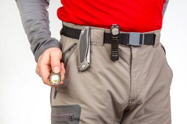 Katlanan bıçak ve turist yürüyüş pantolonunun kemerinde klipsleri olan bir el feneri. EDC ögeleri