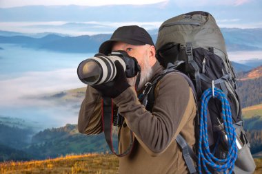 Sırt çantalı sakallı turist fotoğrafçı dağlardaki doğanın güzelliğini fotoğraflıyor. Dağlarda doğa yürüyüşleri