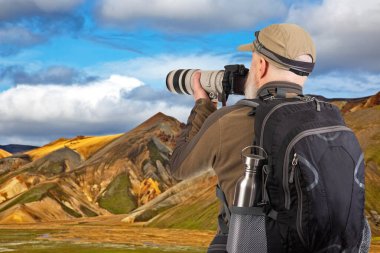 Sırt çantalı bir turist fotoğrafçısı dağlardaki doğanın güzelliğini fotoğraflıyor. Dağlarda doğa yürüyüşleri